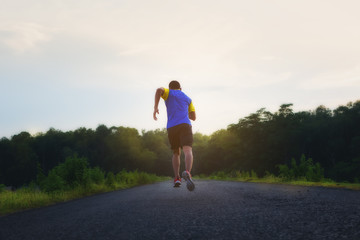 A handsome man jogging on the road with a beautiful nature. Health care concept