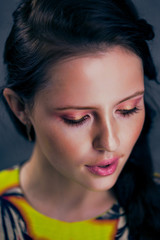 Fototapeta premium Beautiful brunette in yellow dress pink lipa pretty makeup gray background girl smiling