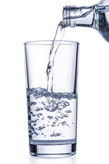 Pouring water from bottle into glass on white background