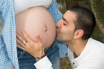 Young man kissing his pregnant wife belly