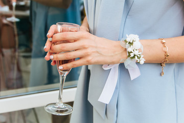 bride in dress with a boutonniere holds a glass of champagne