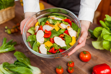 hands holding an healthy checken salad in a bowl