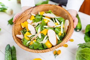 hands holding an healthy checken salad in a bowl