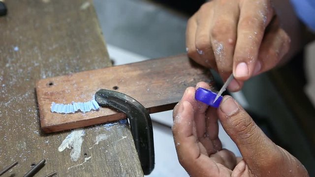 jewlry craftman polishing ring's wax mold by rough half round filing