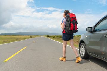 Fototapeta premium female backpacker standing on asphalt road