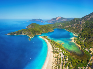 Amazing aerial view of Blue Lagoon in Oludeniz, Turkey. Summer landscape with mountains, green forest, azure water, sandy beach and blue sky in bright sunny day. Travel background. Top view. Nature - obrazy, fototapety, plakaty