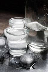 Close-up view of bottle vodka with glasses standing on ice black