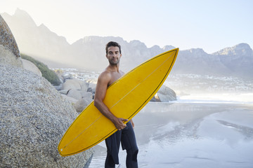 Surfer dude standing on beach, looking at camera