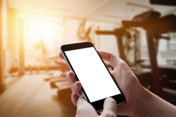 A man hand holding empty screen of smart phone device in Gym.