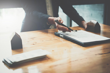 Real estate concept - businessman offer to signs contract with home architectural model at his office