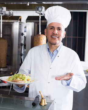 Man chef wearing uniform holding plate  in cafe