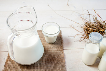 jug of milk and glasses of milk on a wooden rustic table.