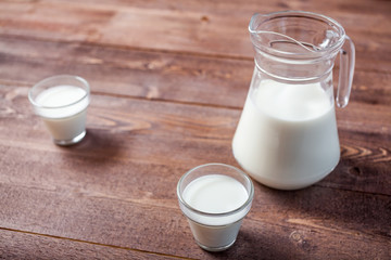 milk and glasses of milk on a wooden rustic table.