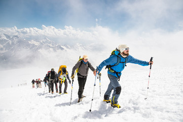 A group of mountaineers climbs to the top of a snow-capped mountain - Powered by Adobe