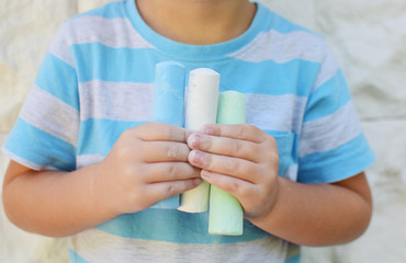 kid holding colored chalk paints for drawing