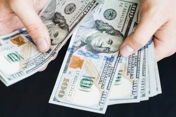 The white young man counts the money, one hundred new dollar bills on a black background close plan. Concepts of business and finance. top view .