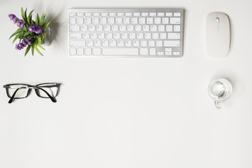 White hipster office desk with computer gadgets and supplies. Top view with copy space, flat lay.