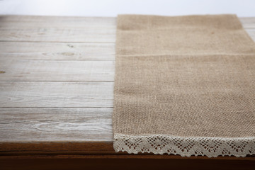 Canvas napkin with lace. Burlap hessian sacking on white wooden table background top view