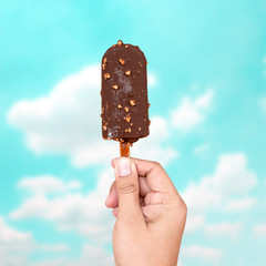 Hand holding chocolate ice cream on blur sky