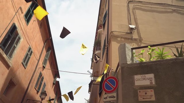 Small flaglets hanging on the streets of Monte Argentario and seen the houses on the road side