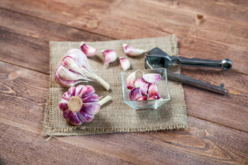 Garlic Cloves Garlic Bulb and Garlic Press on a wooden vintage rustic table.