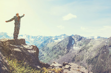 Hiker standing on top of a mountain with raised hands and enjoying sunrise
