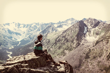 Man sit on sharp cliff above valley in rocky mountains park
