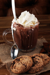 A messy cup with hot chocolate and chocolate chip cookies.