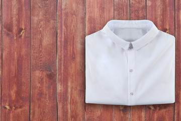 Folded white shirt on brown wood table with empty space for copy, back to school or job review...