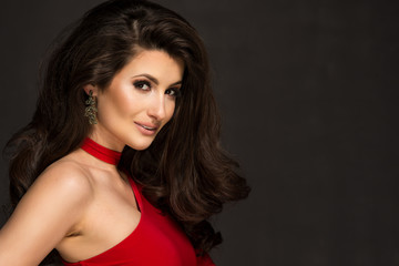 Sensual beautiful blonde woman posing in red dress. Girl with long curly hair.