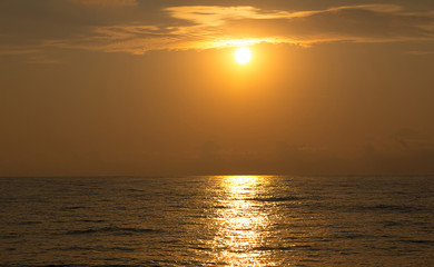 Bright orange sunset over the sea leaving in the distance on the surface of the water