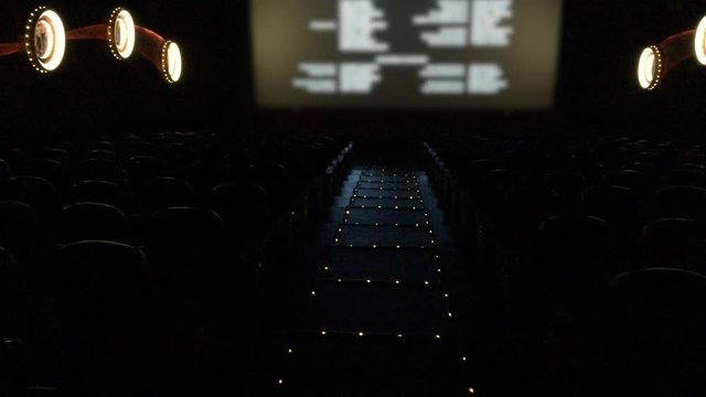 Medium long shot of empty movie theater with final credits rolling