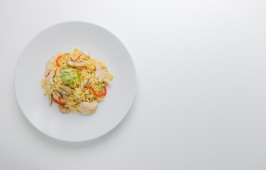 Stir-fry noodles with chicken meat, mushroom and red capsicum in a plate on white background, copy space, close-up..