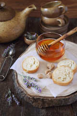Lavender honey in glass jar, flowering lavender and slices of baguette