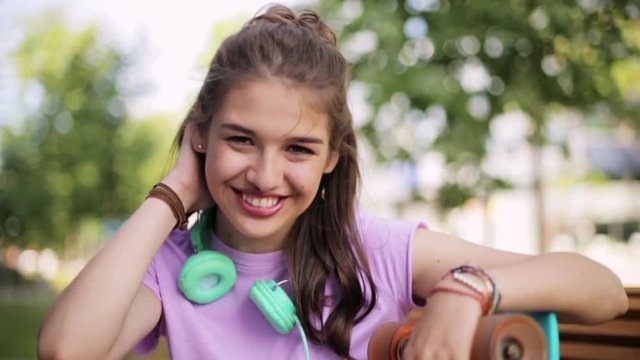 happy teenage girl with headphones and longboard