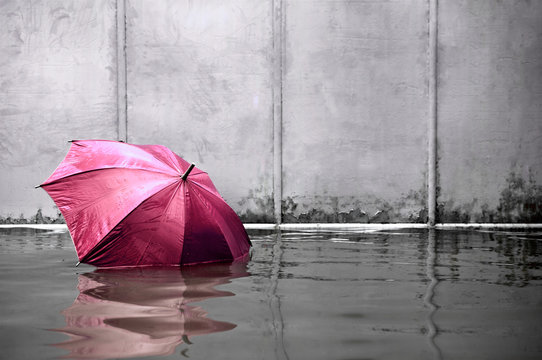 Pink umbrella floating concept. Flooded on street. .Waiting for help me after the rain. Black and white colors. Close up.