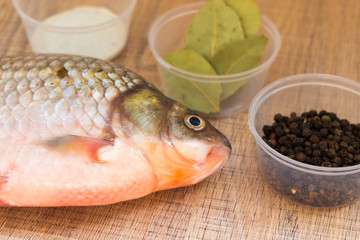 Fresh fish carp on the spice lies on the Board and the plate