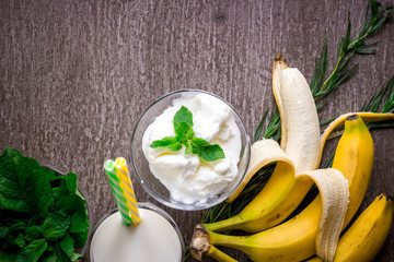 Ice cream with fresh banana and mint on wooden table.