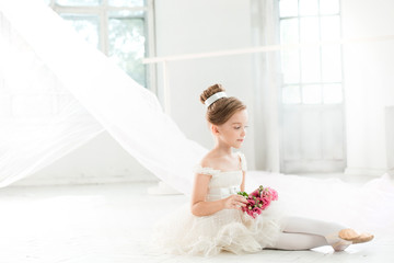 The little balerina in white tutu in class at the ballet school