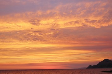 Fototapeta na wymiar Bright colored sunset sky above the sea. On the coast of Dobra Voda, Montenegro, south-east Europe.