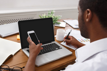 African-american businessman in office with mobile and laptop