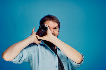 Man with a beard on a blue background holds a bottle of beer, alcohol, portrait, emotions