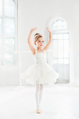Little ballerina girl in a tutu. Adorable child dancing classical ballet in a white studio. © master1305