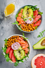 Healthy salad bowl with salmon, grapefruit, spicy chickpeas, avocado, red onion and arugula