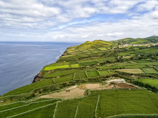 Aerial view of fields and Atlantic Ocean with the village of Ginetes in the background on Sao Miguel Island in Portugal.