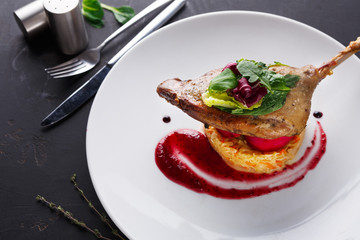Restaurant meals. Duck confit with vegetables on black background
