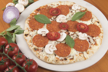 Uncooked pepperoni  pizza with tomatoes and raw ingredients 