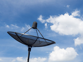 Black satellite dish or TV antennas install on the house roof on blue sky cloudy background.