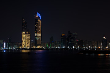 Fototapeta premium Abu Dhabi buildings skyline from the sea at night