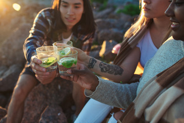 Two girls and guy toasting with glasses of refreshing cocktail